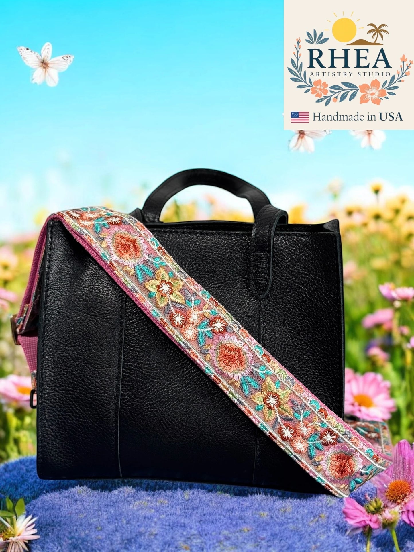 Black handbag with a colorful floral purse strap against a natural background, featuring the RHEA brand.
