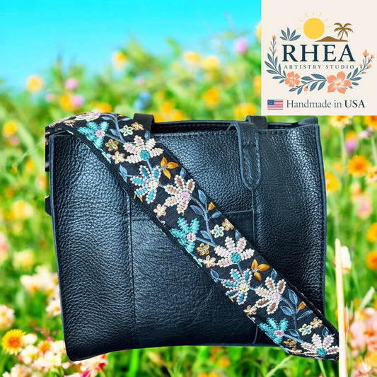 Black leather bag with a floral embroidered strap against a blurred natural background