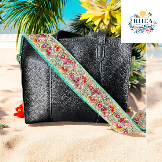 Aqua strap with trillium flowers and tropical tones, styled on a black bag by the shore.