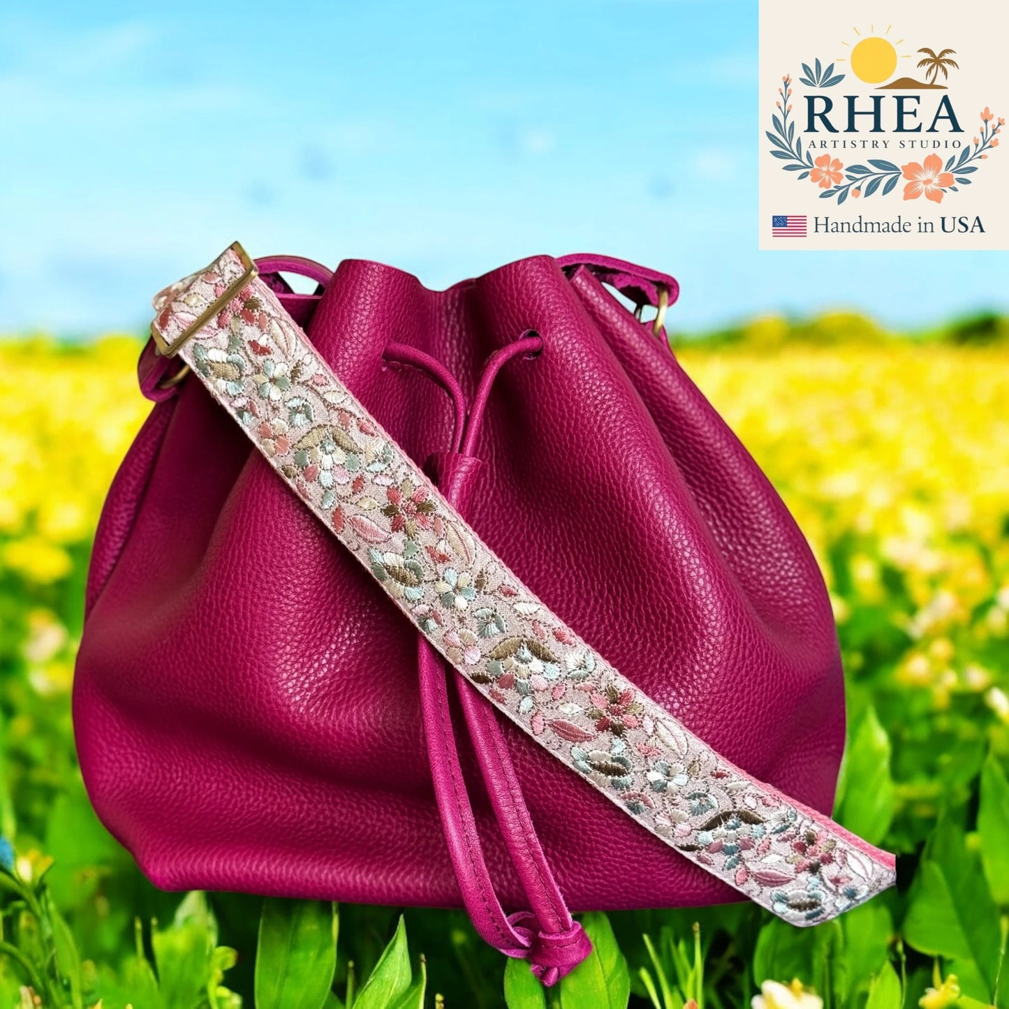 Pink leather bag with floral purse strap against a natural background, featuring the RHEA Artistry Studio logo.