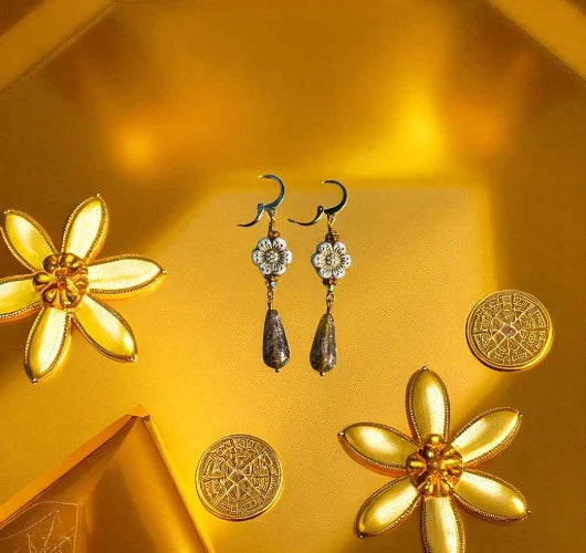 Gold flower-shaped earrings and coins on a yellow background
