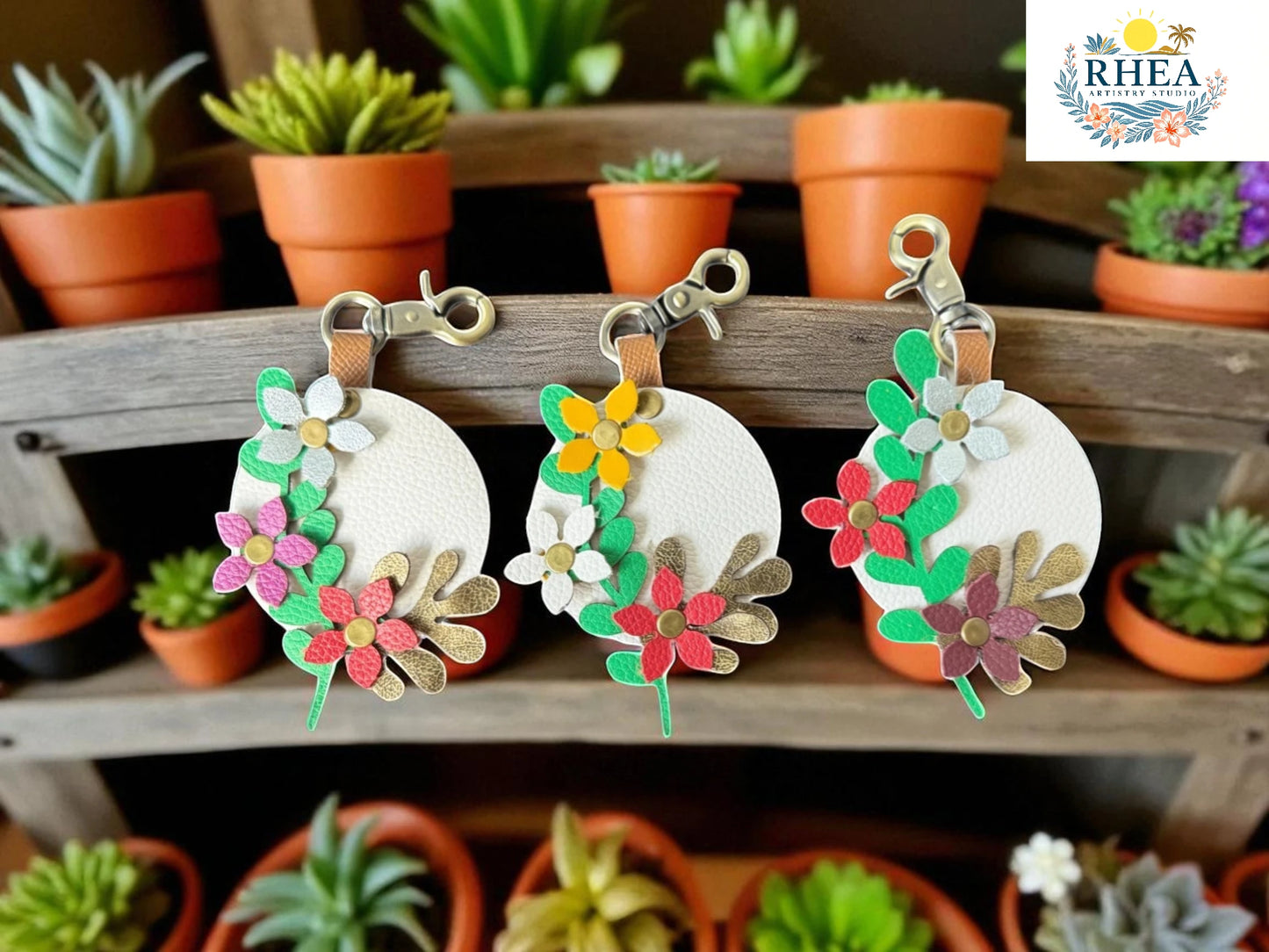 Floral keychains on a wooden surface with potted plants in the background