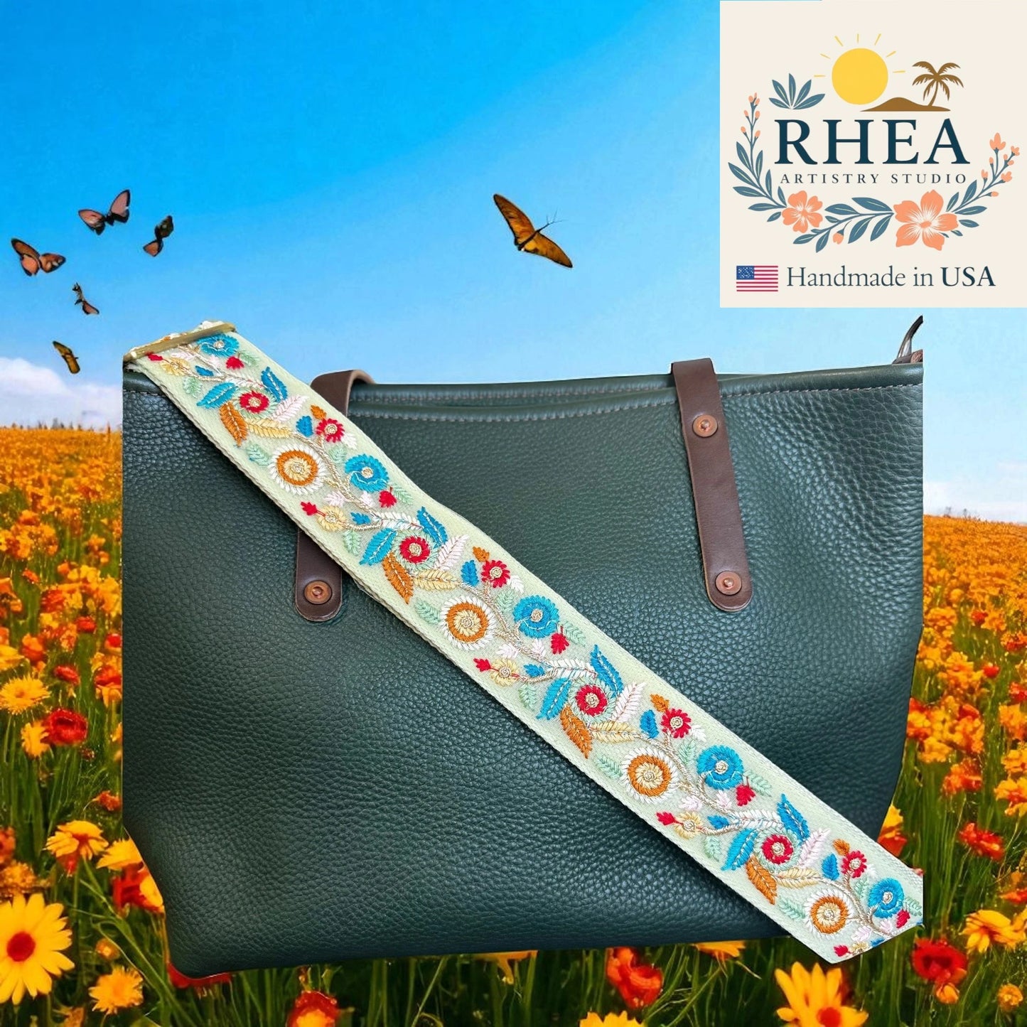 Green handbag with a floral strap in a field of flowers and butterflies, featuring RHEEA Artistry Studio branding.