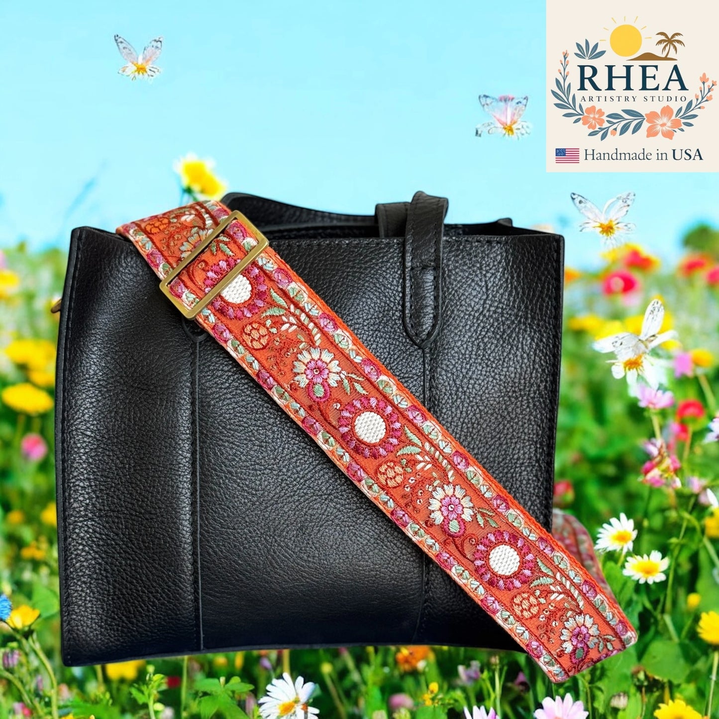 Black handbag with a colorful floral purse strap against a floral background, featuring the RHEA brand.