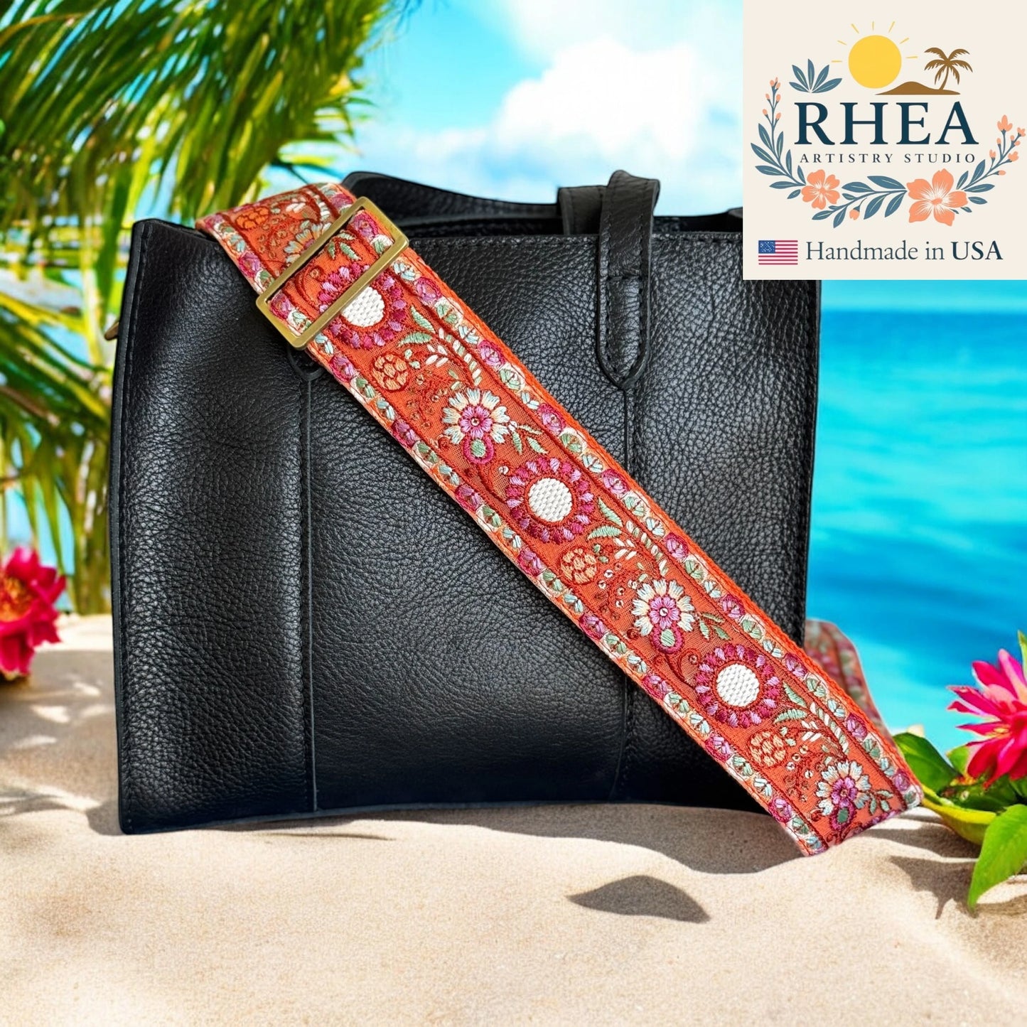 Black handbag with a colorful floral purse strap on a beach background, featuring the Rhea Artistry Studio logo.