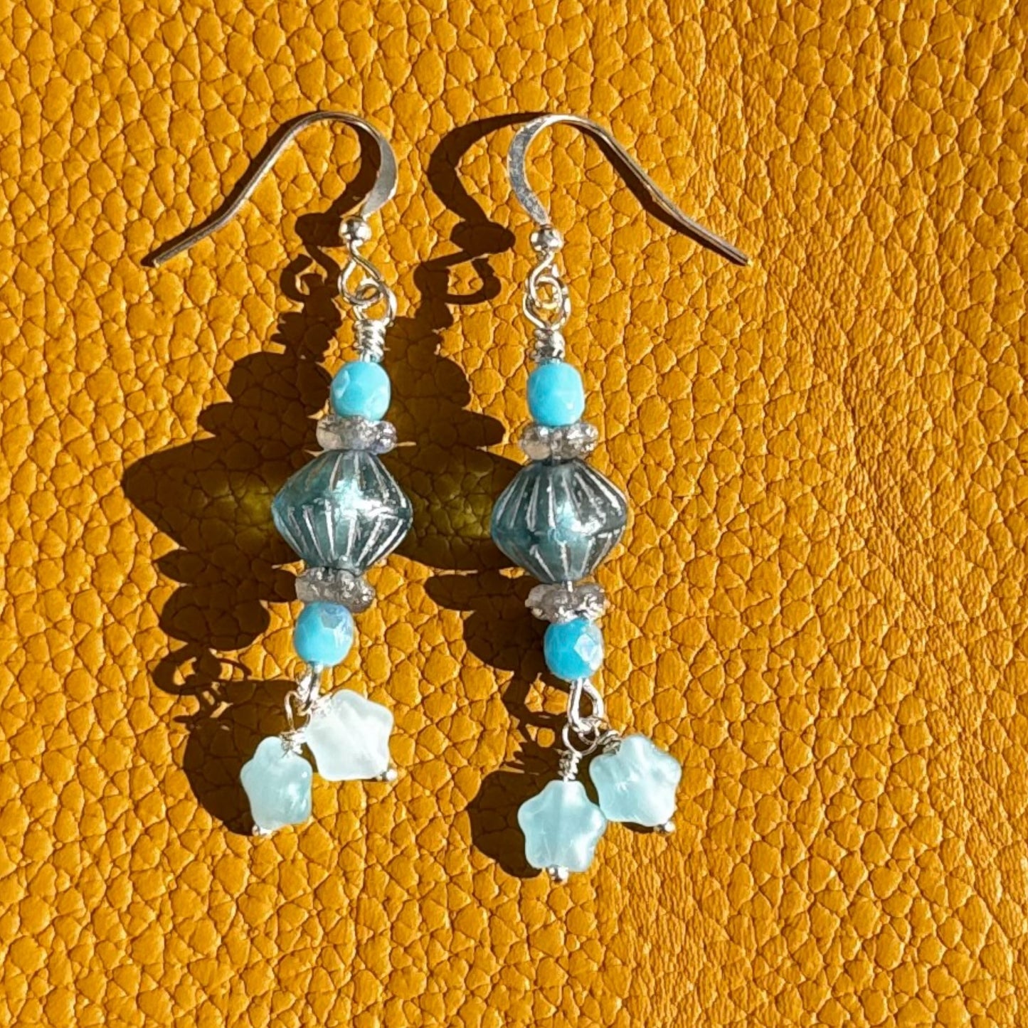 Pair of earrings with blue and clear beads on a textured orange background