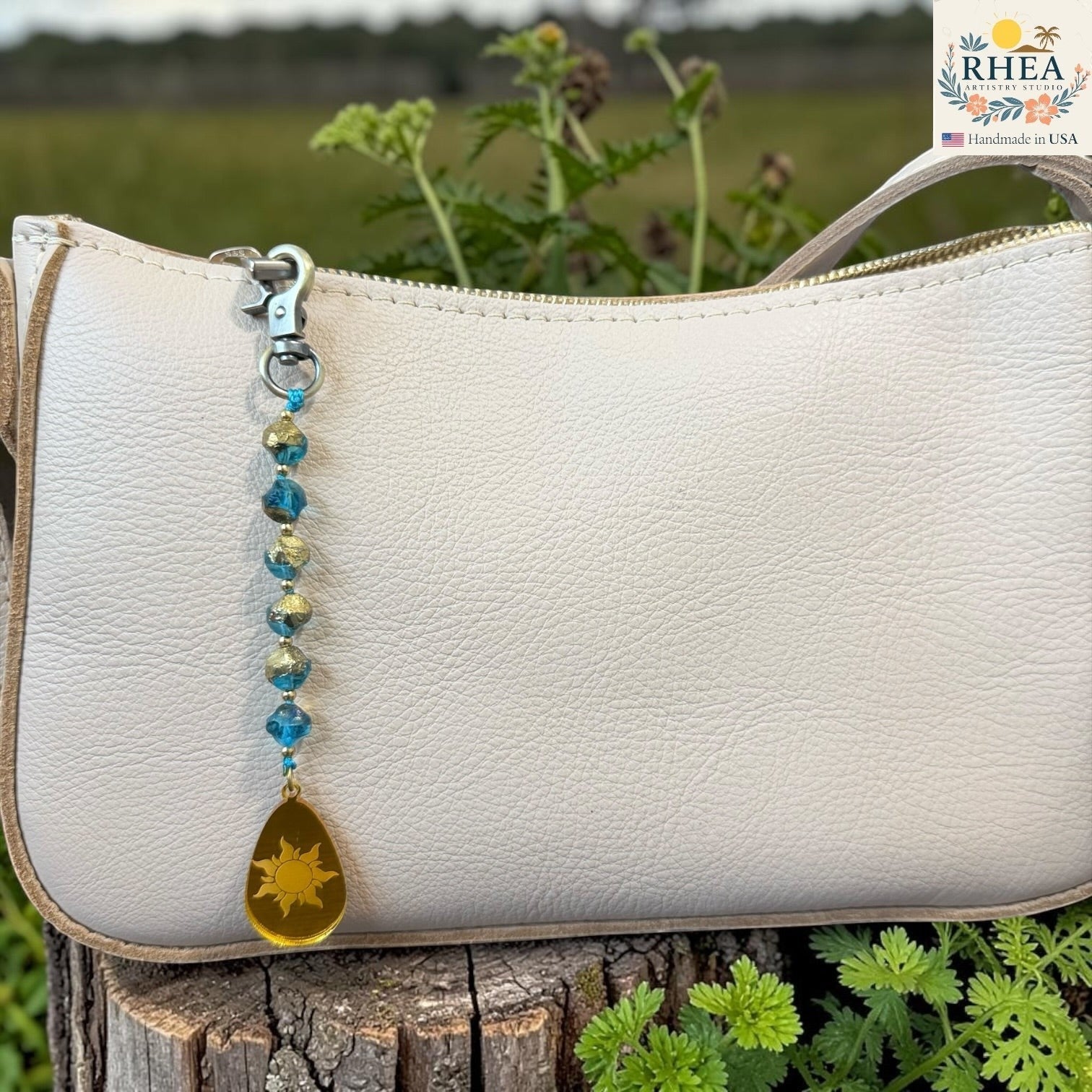 Handmade artisan bag charms displayed on a blush background with glass beads and engraved pendants