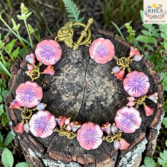 Handmade pink floral glass bead bracelet with brass toggle clasp on tree stump