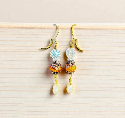 Pair of earrings with colorful beads on a light wooden surface