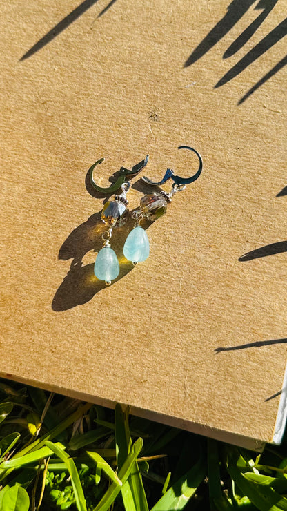 A pair of cathedral-shaped silver drop earrings with light blue colored glass.