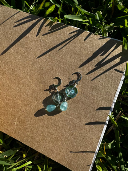 A pair of cathedral-shaped silver drop earrings with light blue colored glass.