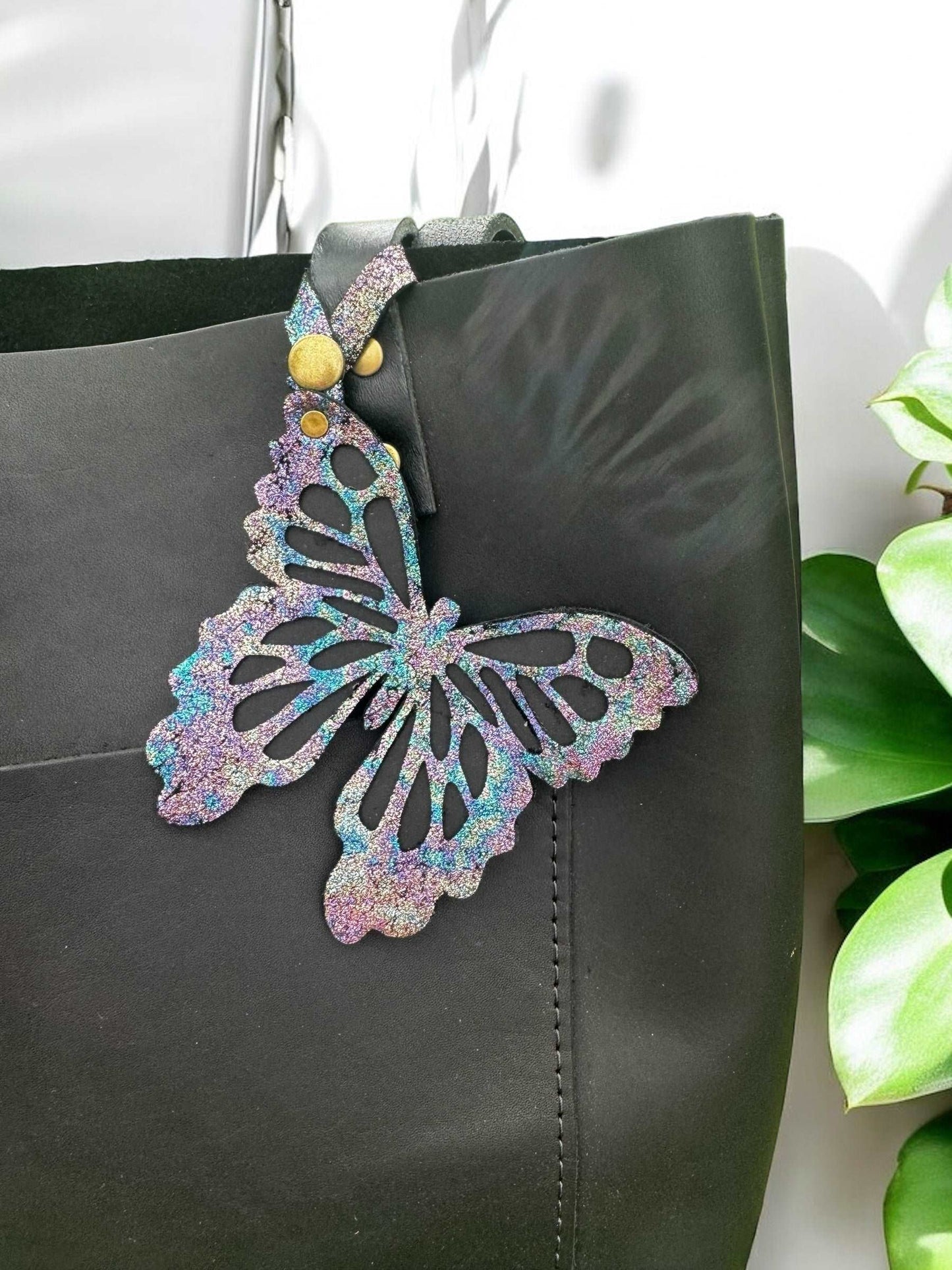 Unique leather butterfly charm with a chameleon-like color-shifting effect, crafted from halo metallic leather with a crackled texture and a snap closure for versatile use.