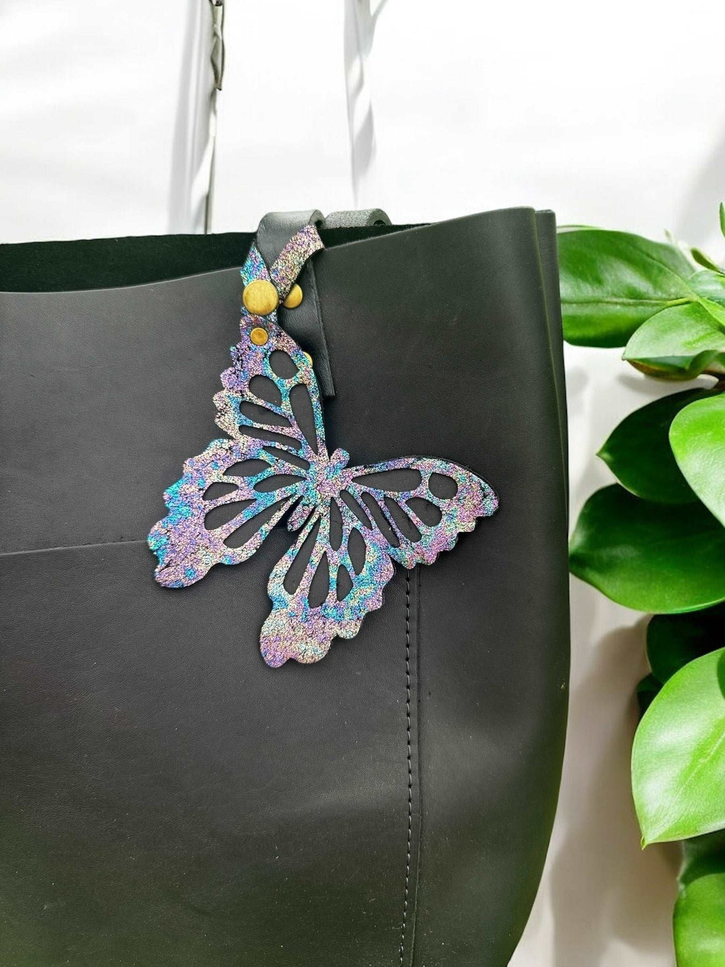 Unique leather butterfly charm with a chameleon-like color-shifting effect, crafted from halo metallic leather with a crackled texture and a snap closure for versatile use.