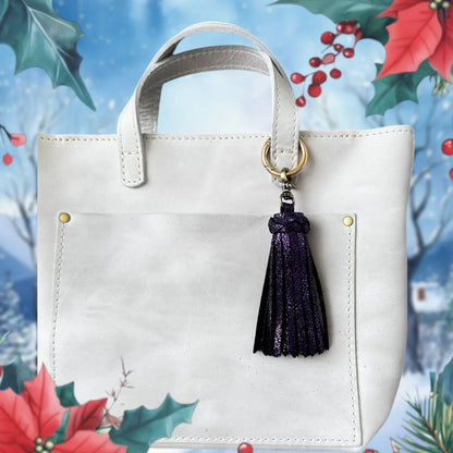 White handbag with a purple tassel on a decorative background with holly and berries.
