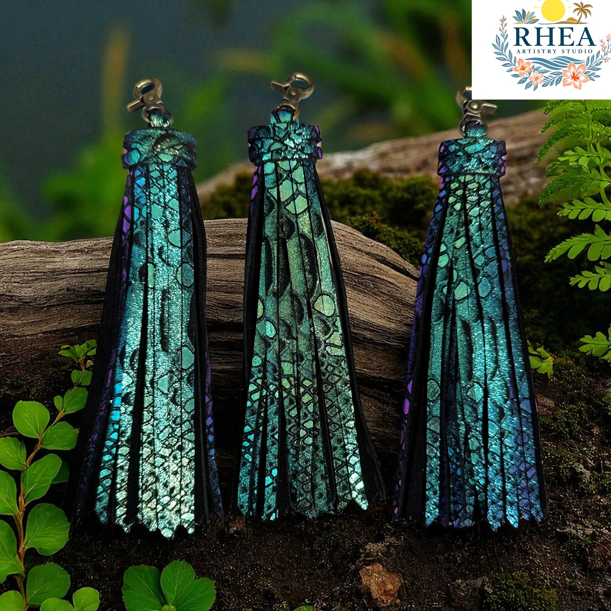 Three teal and purple earrings on a wooden log with a blurred natural background