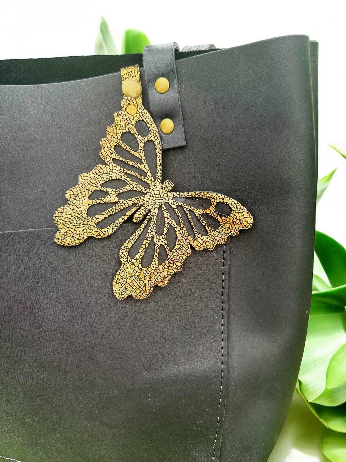 Luxurious leather butterfly charm in a crackled gold finish, made from halo metallic leather, with a snap closure for easy use as a purse accessory or keychain.