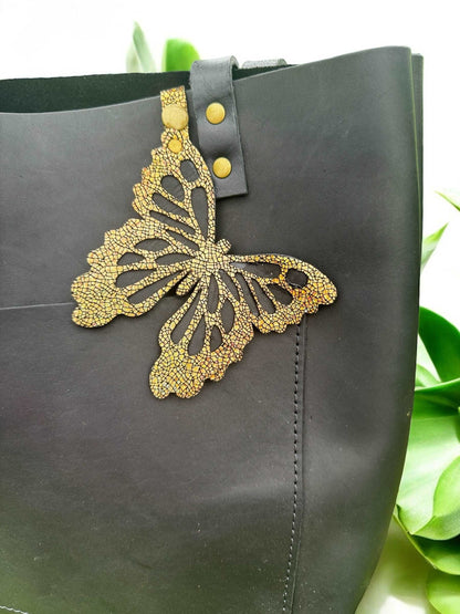 Luxurious leather butterfly charm in a crackled gold finish, made from halo metallic leather, with a snap closure for easy use as a purse accessory or keychain.