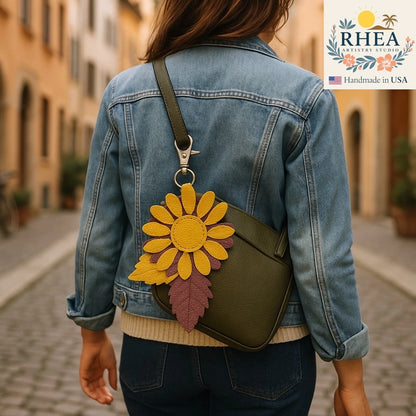 Person wearing a denim jacket with a green bag featuring a leather bag charm, set against an urban background.