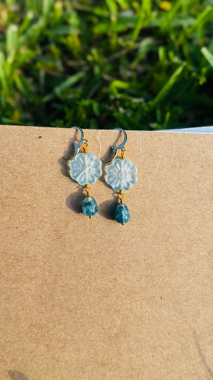 Floral earrings with blue beads on an old book