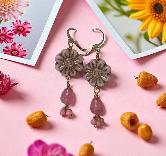 Floral earrings with pink beads on a pink background with flowers and fruits.