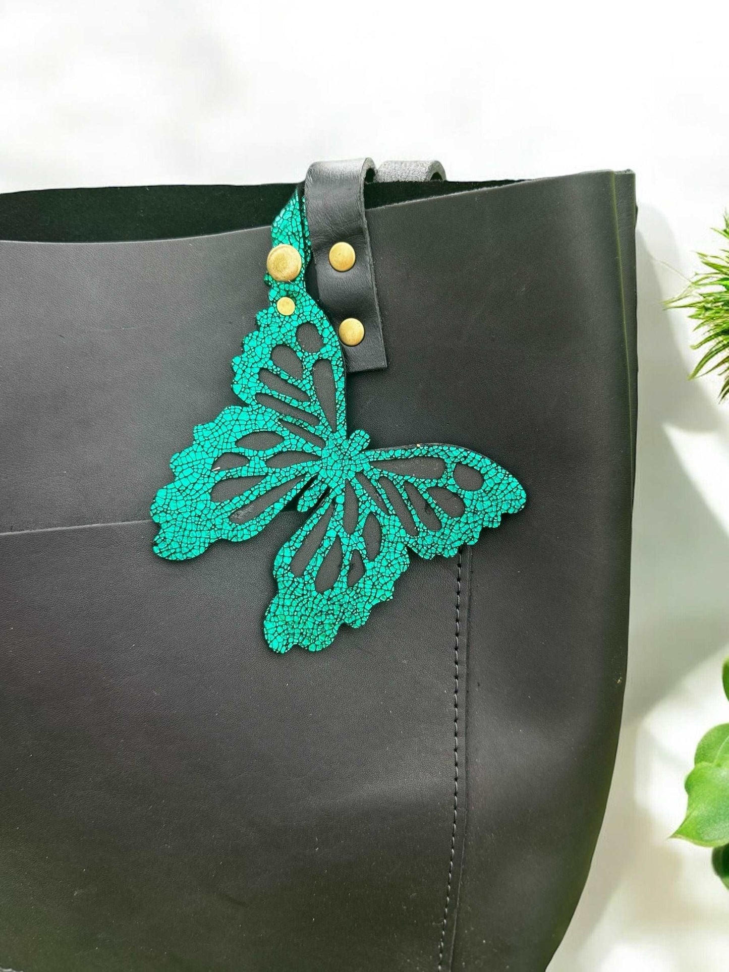 Handcrafted leather butterfly charm in a lush emerald green, featuring halo metallic leather with a crackled look and a convenient snap closure for attachment.