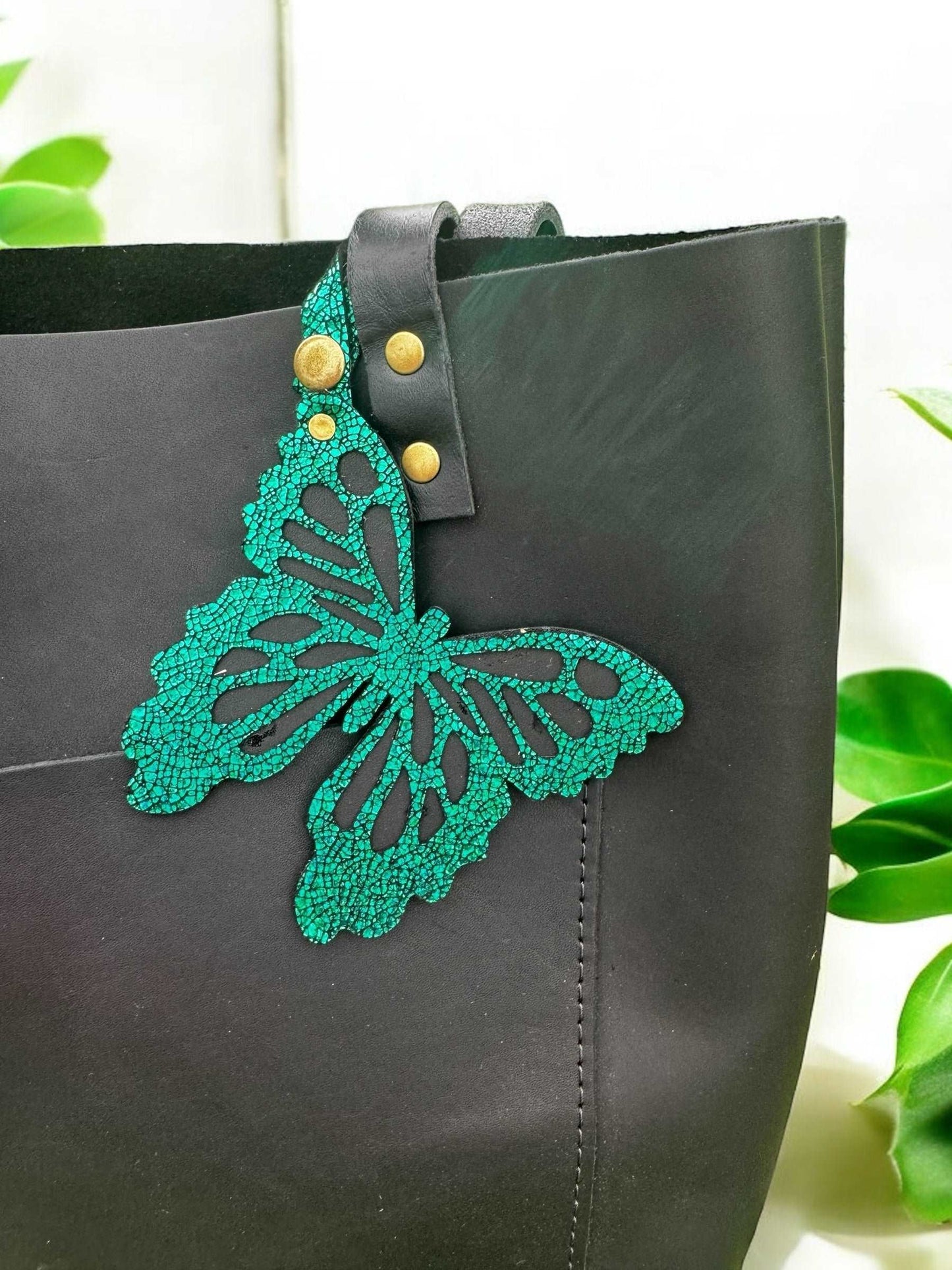 Handcrafted leather butterfly charm in a lush emerald green, featuring halo metallic leather with a crackled look and a convenient snap closure for attachment.