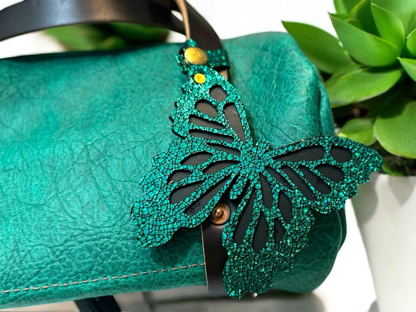 Handcrafted leather butterfly charm in a lush emerald green, featuring halo metallic leather with a crackled look and a convenient snap closure for attachment.