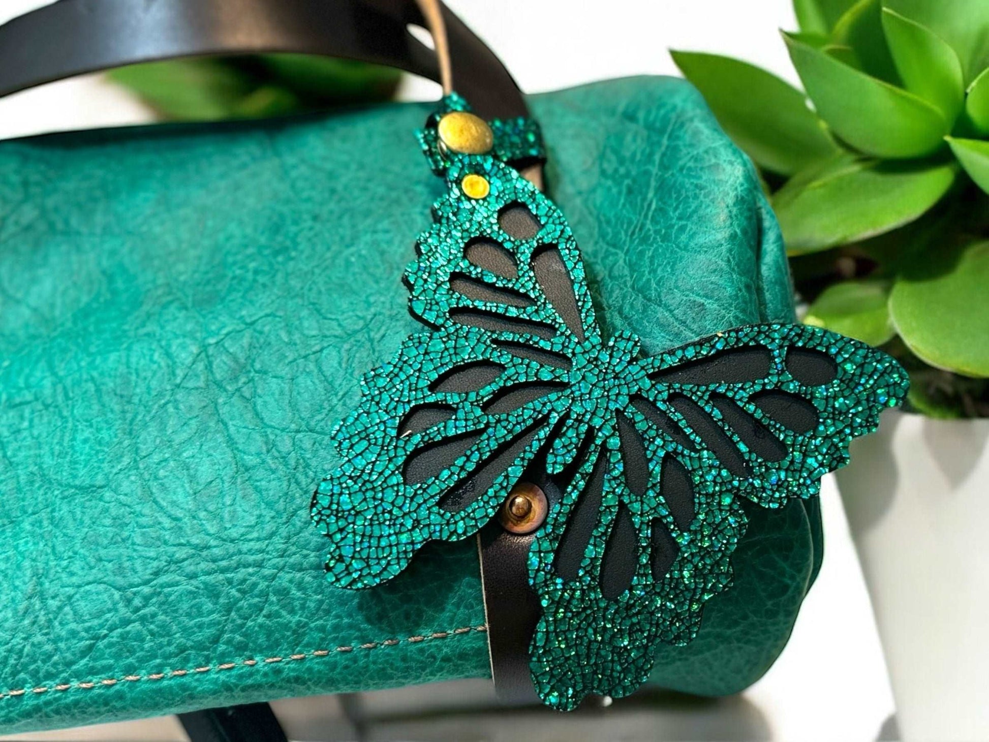 Handcrafted leather butterfly charm in a lush emerald green, featuring halo metallic leather with a crackled look and a convenient snap closure for attachment.