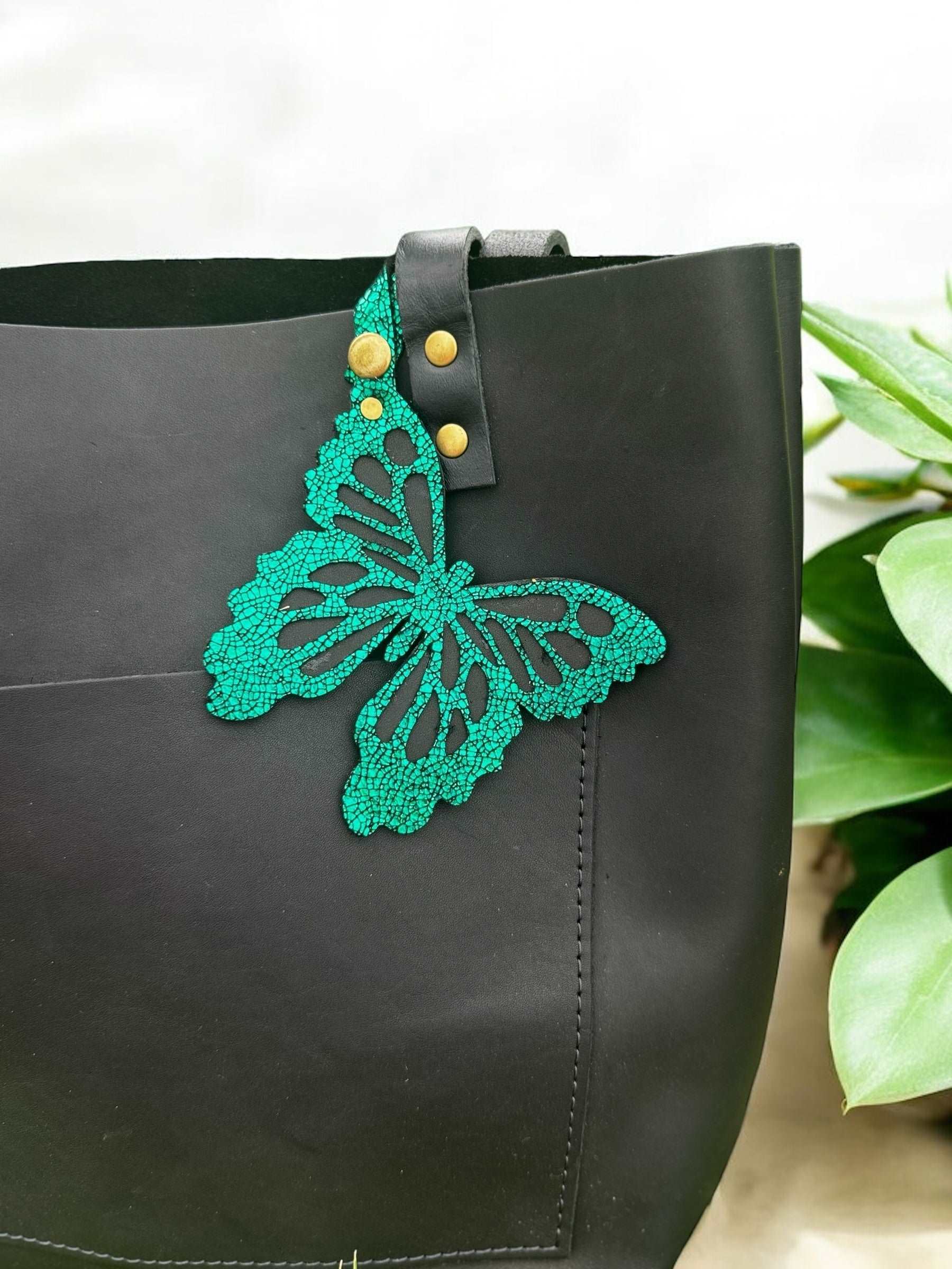 Handcrafted leather butterfly charm in a lush emerald green, featuring halo metallic leather with a crackled look and a convenient snap closure for attachment.