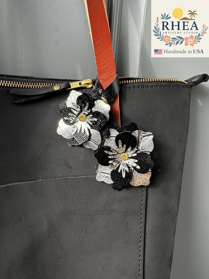 Close-up of the Everbloom Leather Bag Charm Double in black and silver, featuring two layered handcrafted blossoms with soft metallic and matte finishes.