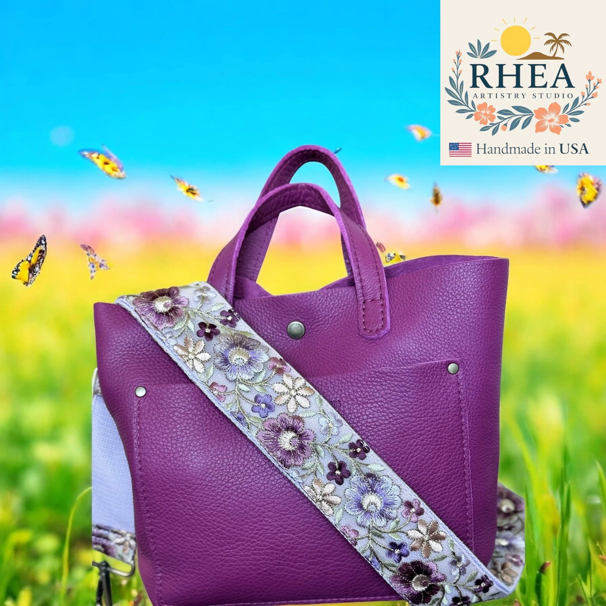 Purple handbag with floral purse strap on a colorful background, featuring the Rhea Artistry Studio logo.