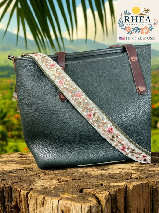 Green handbag with floral bag strap on a wooden surface, with 'RHEA' branding in the corner.