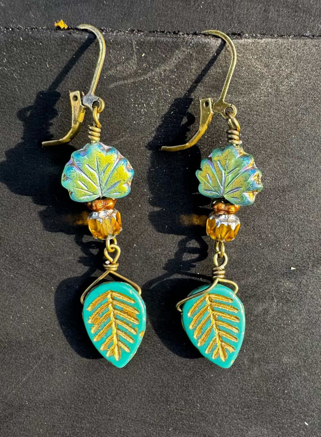 Pair of earrings with leaf designs on a black bag