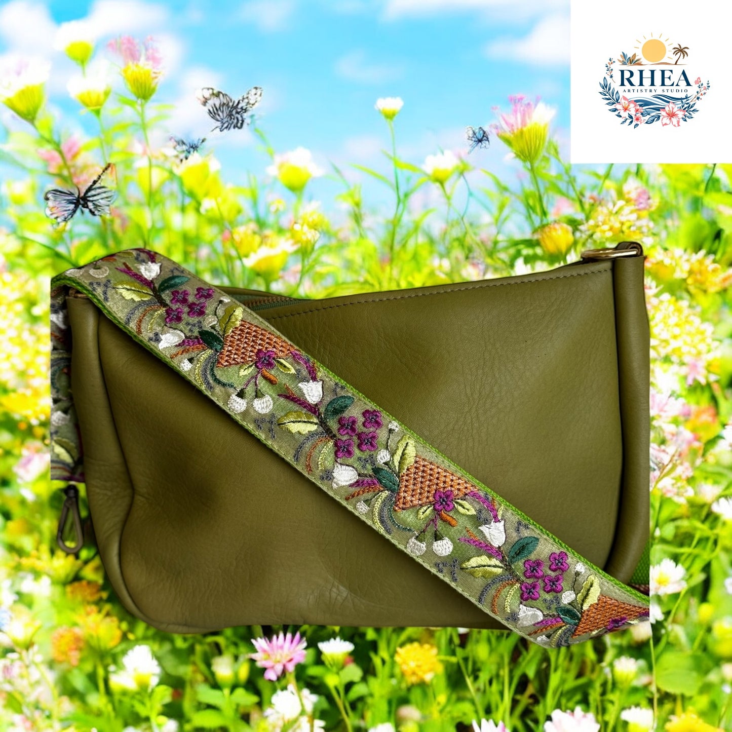 Embroidered strap with deep green base featuring plum and white flowers, copper basket weave embroidery, and leafy vine details, displayed on an olive leather bag.