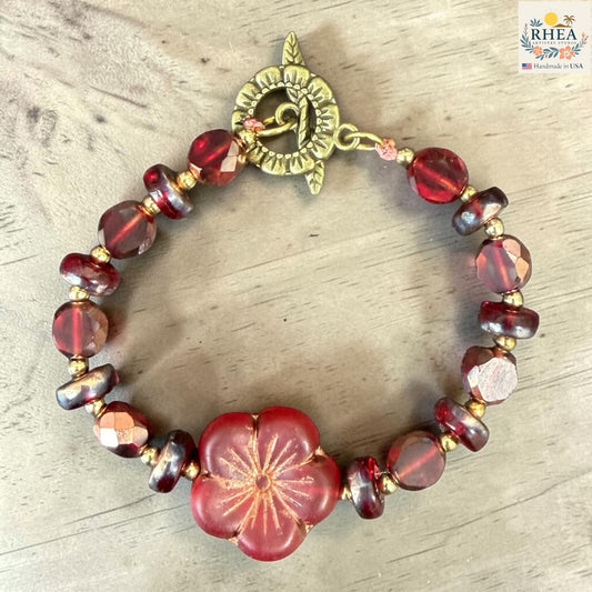 Bracelet with red and gold beads on a wooden surface