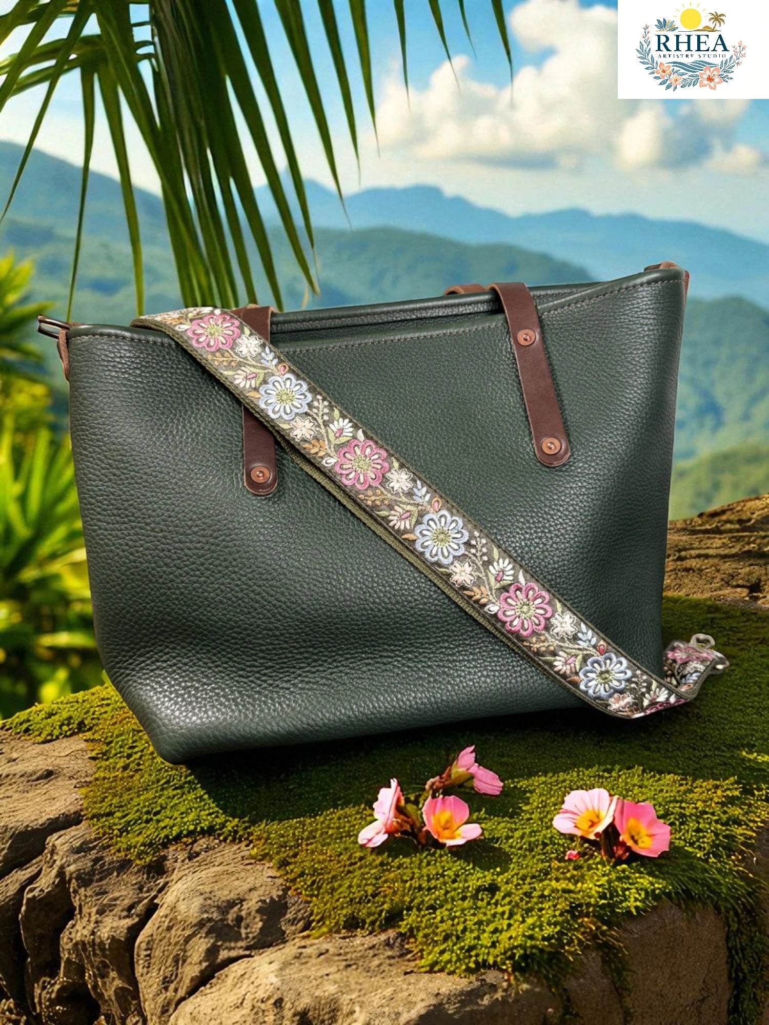 Green leather handbag with floral strap on a rock with a mountainous background