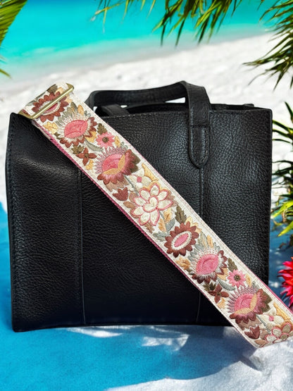 Ethically crafted embroidered replacement purse strap in pink featuring intricate sunflower motifs on a white background at beach