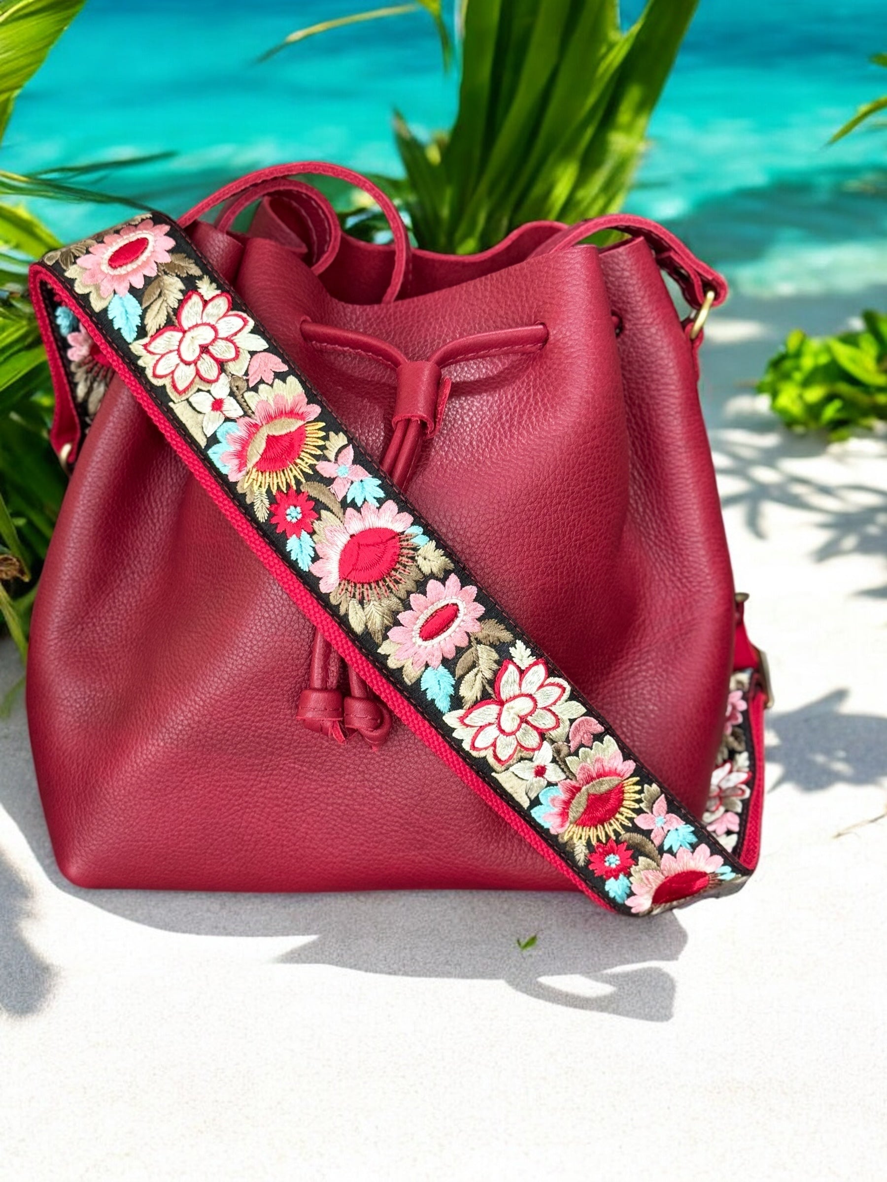 Ethically crafted embroidered replacement purse strap in red featuring intricate sunflower motifs on a black background at beach