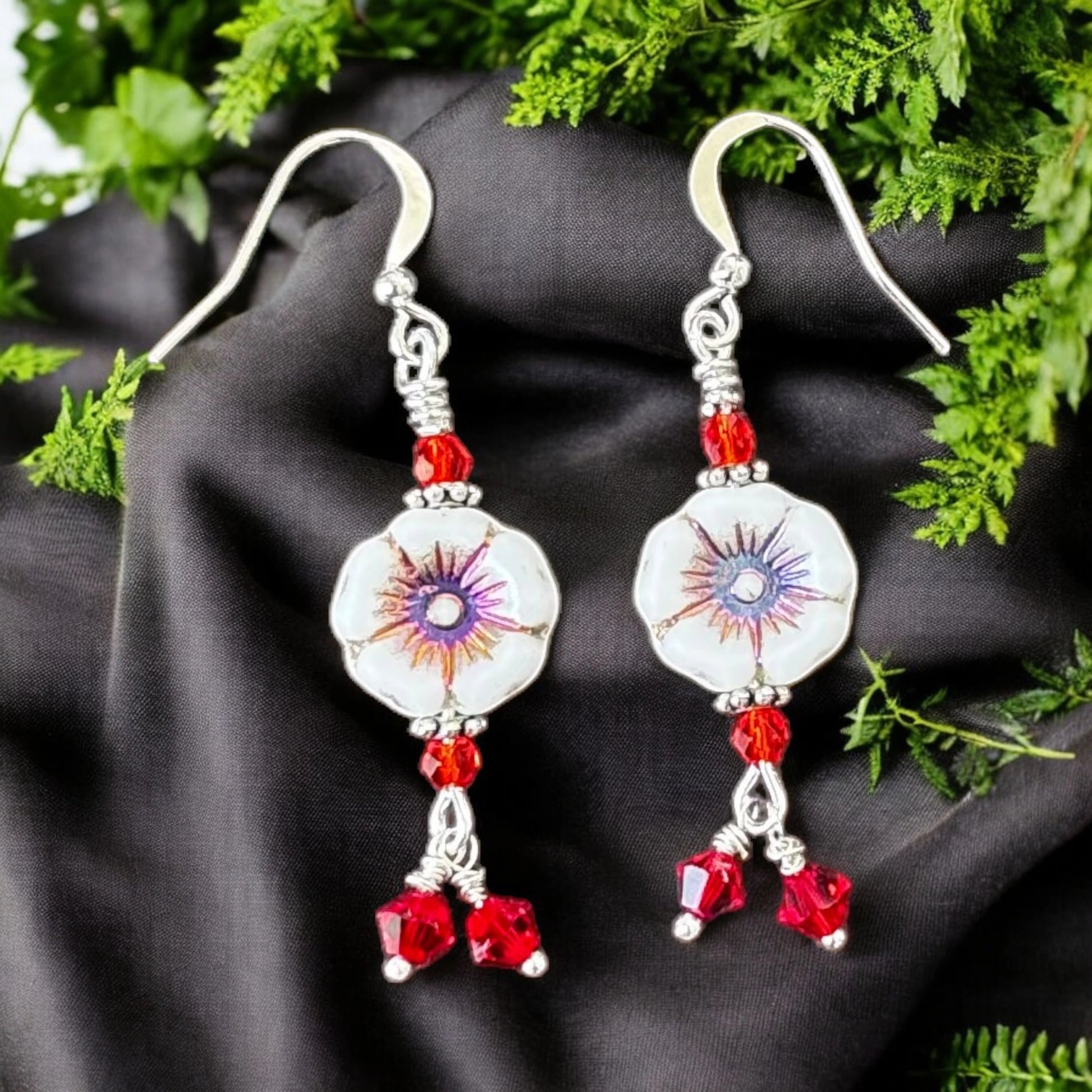 Pair of earrings with red beads on a black fabric background