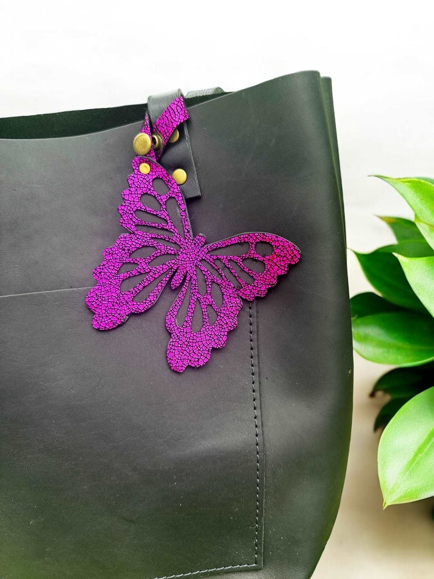 Bold leather butterfly charm in a striking hot pink/fuchsia color, made with halo metallic leather and a crackled finish, designed with a snap closure for accessorizing.