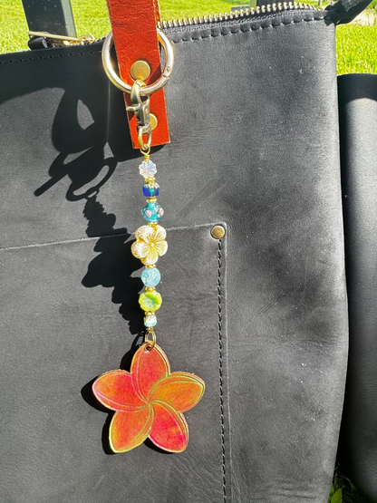 Decorative keychain with colorful beads and a red flower charm on a black bag.