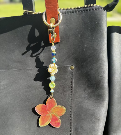 Decorative keychain with colorful beads and a red flower charm on a black bag.