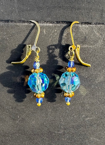 Gold and blue beaded earrings on a black bag