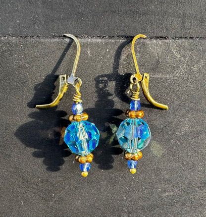 Gold and blue beaded earrings on a black bag