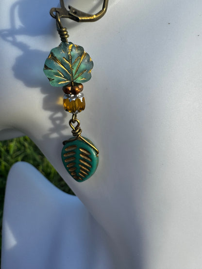 Pair of earrings with leaf designs on a model