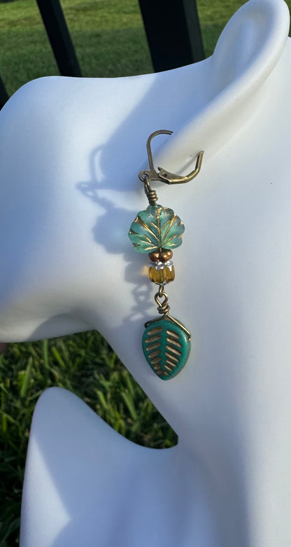 Pair of earrings with leaf designs on a model