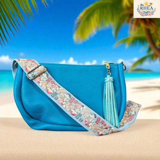 Blue handbag with a  handmade floral strap on a beach background