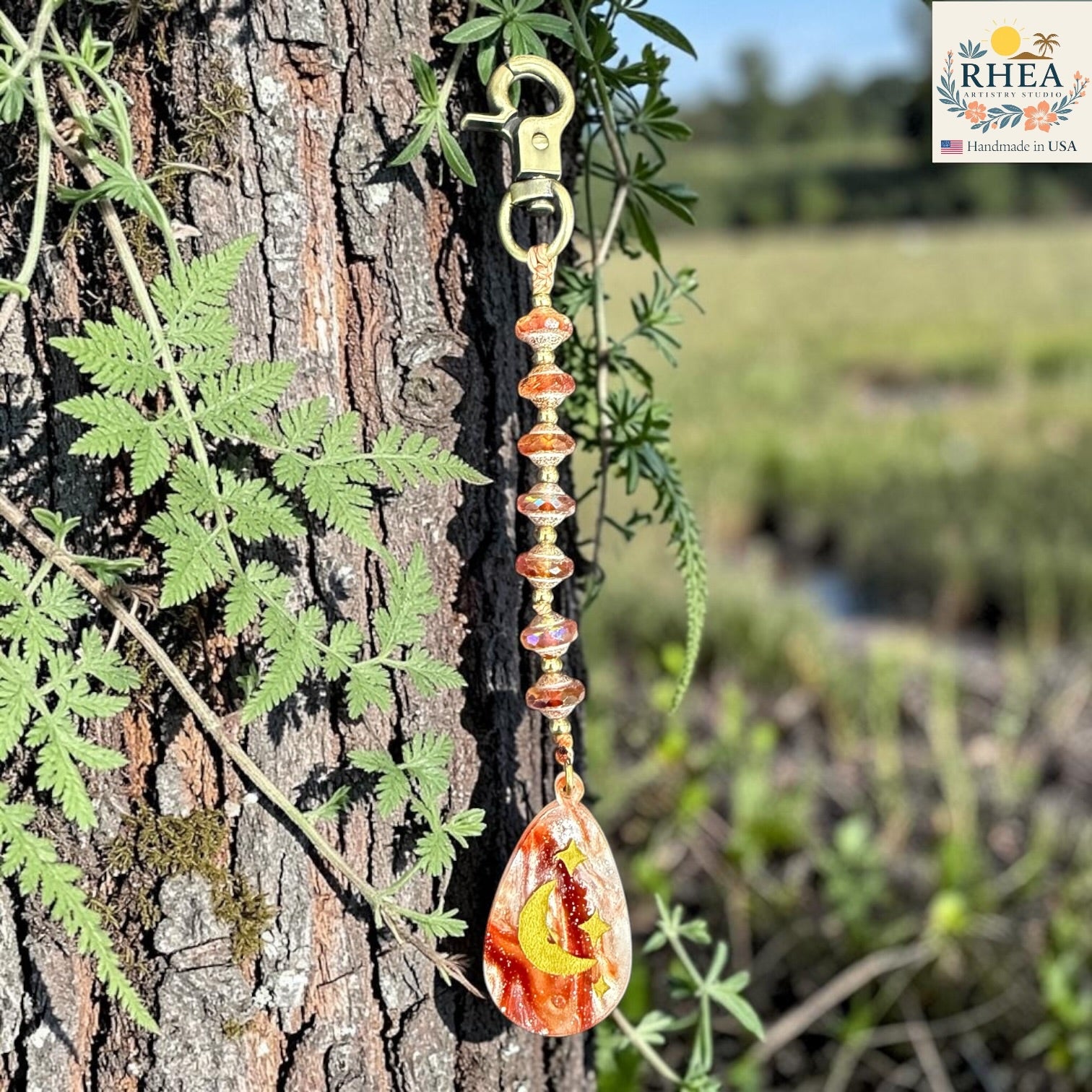Decorative keychain with a sun design hanging from a tree