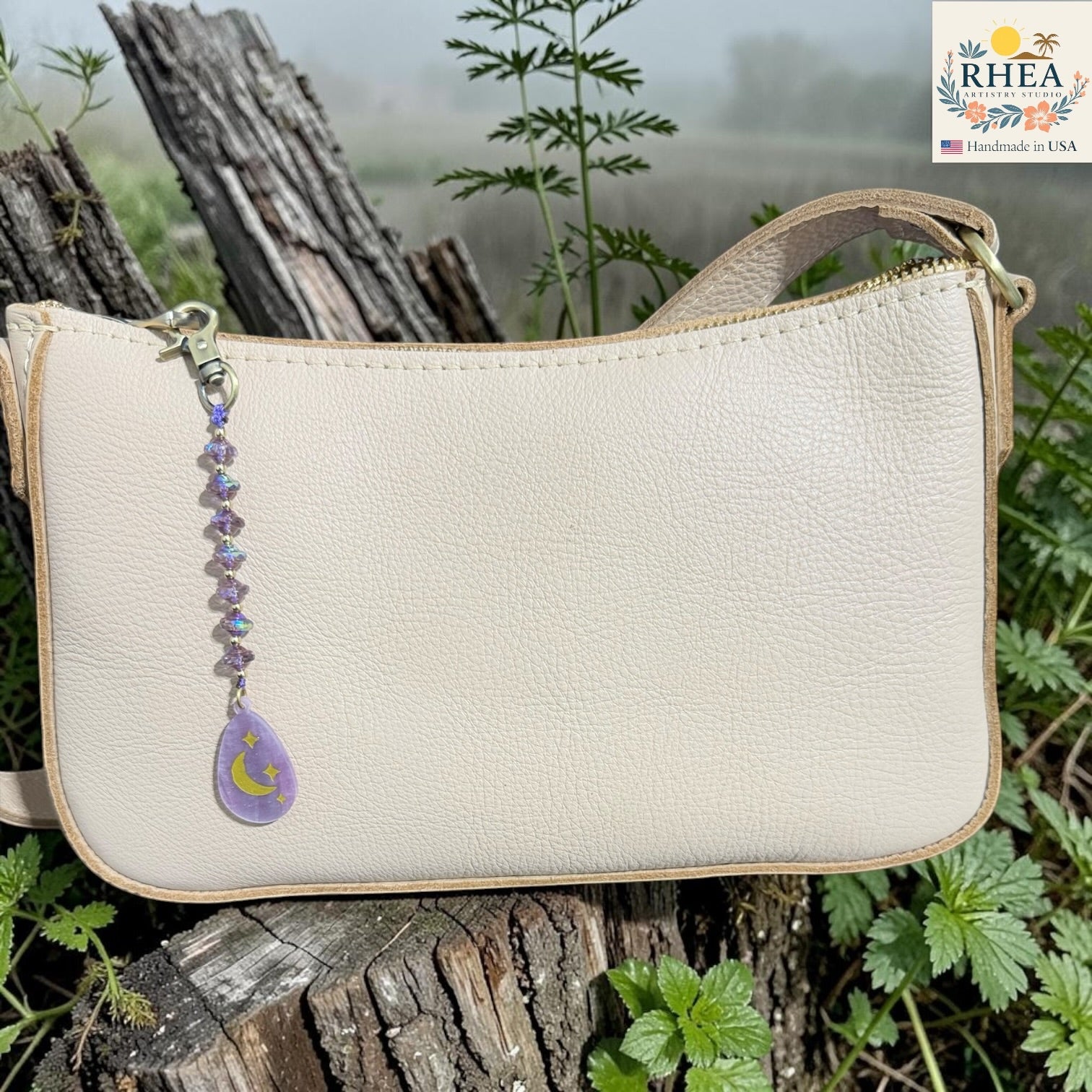 Beige handbag with a decorative keychain on a natural background
