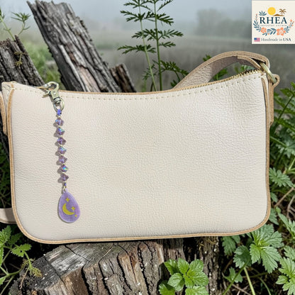 Beige handbag with a decorative keychain on a natural background